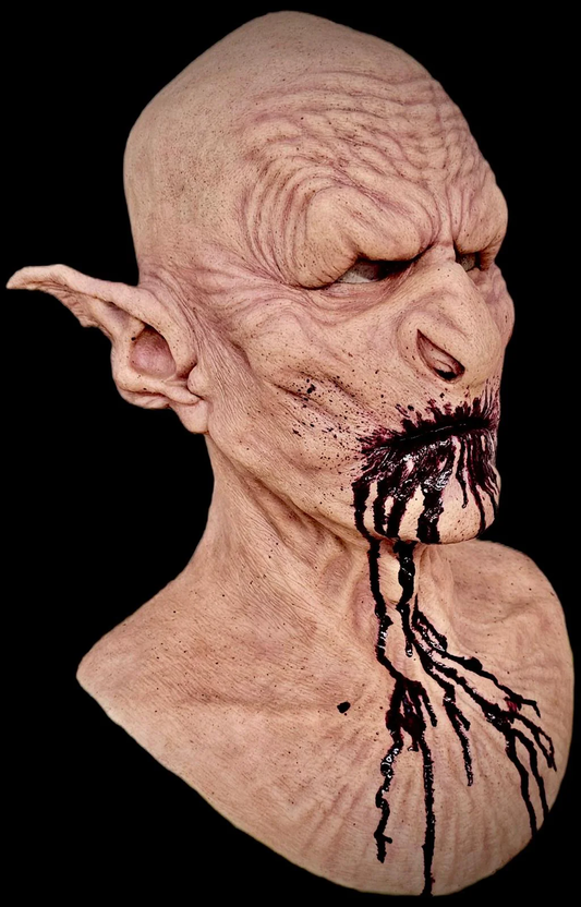 Mr E Masks realistic silicone Orc mask in flesh-tone finish with hand-painted blood dripping from the mouth, featuring deeply textured wrinkled skin and pointed ears — shown against a black background