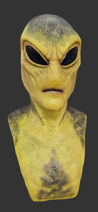 Green alien mask with black specks on a gray background