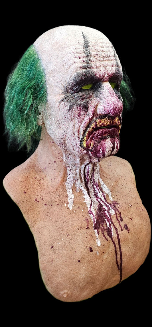 Old man mask with green hair and white face makeup, resembling a clown with bloody mouth