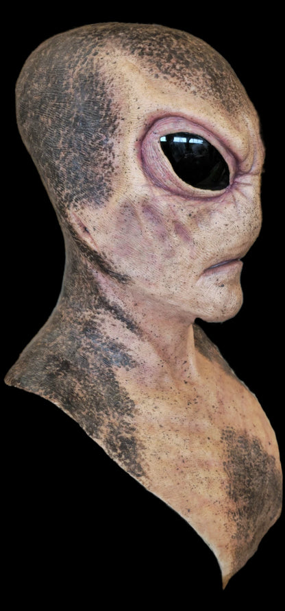 Close-up of an alien head mask with a large eye on a black background